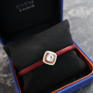 Red bracelet with a cushion cut polki diamond in an open jewellery box on a marble surface